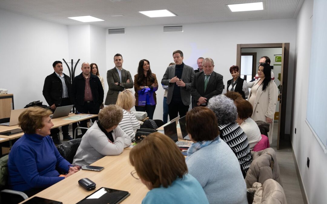 Participantes del programa de Capacitación Digital de la Diputación de Jaén trabajan con ordenadores portátiles y tablets en un aula informática, mientras responsables institucionales observan el desarrollo de la actividad.